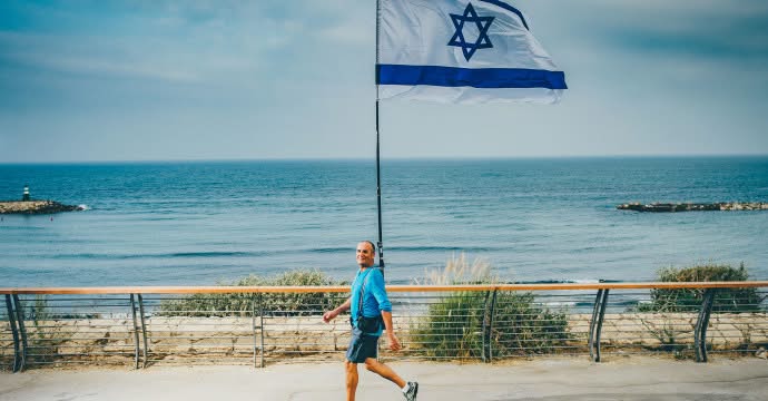 חיים הולך עם הדגל לאורך חוף הים בתל אביב