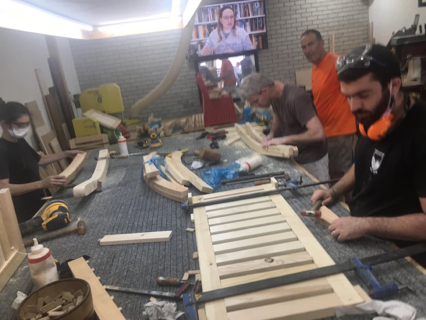 משתתפי החוג עובדים סביב שולחן העבודה על חלקי ספסל