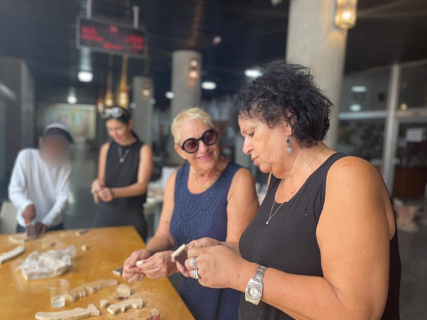 נשים מרכיבות חלקי עץ סביב שולחן העבודה