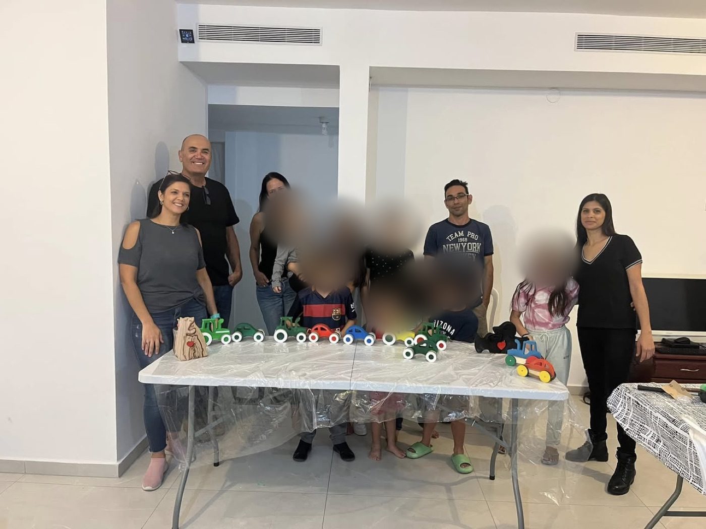 ילדים והורים מסביב לשולחן עם מכוניות העץ שבנו